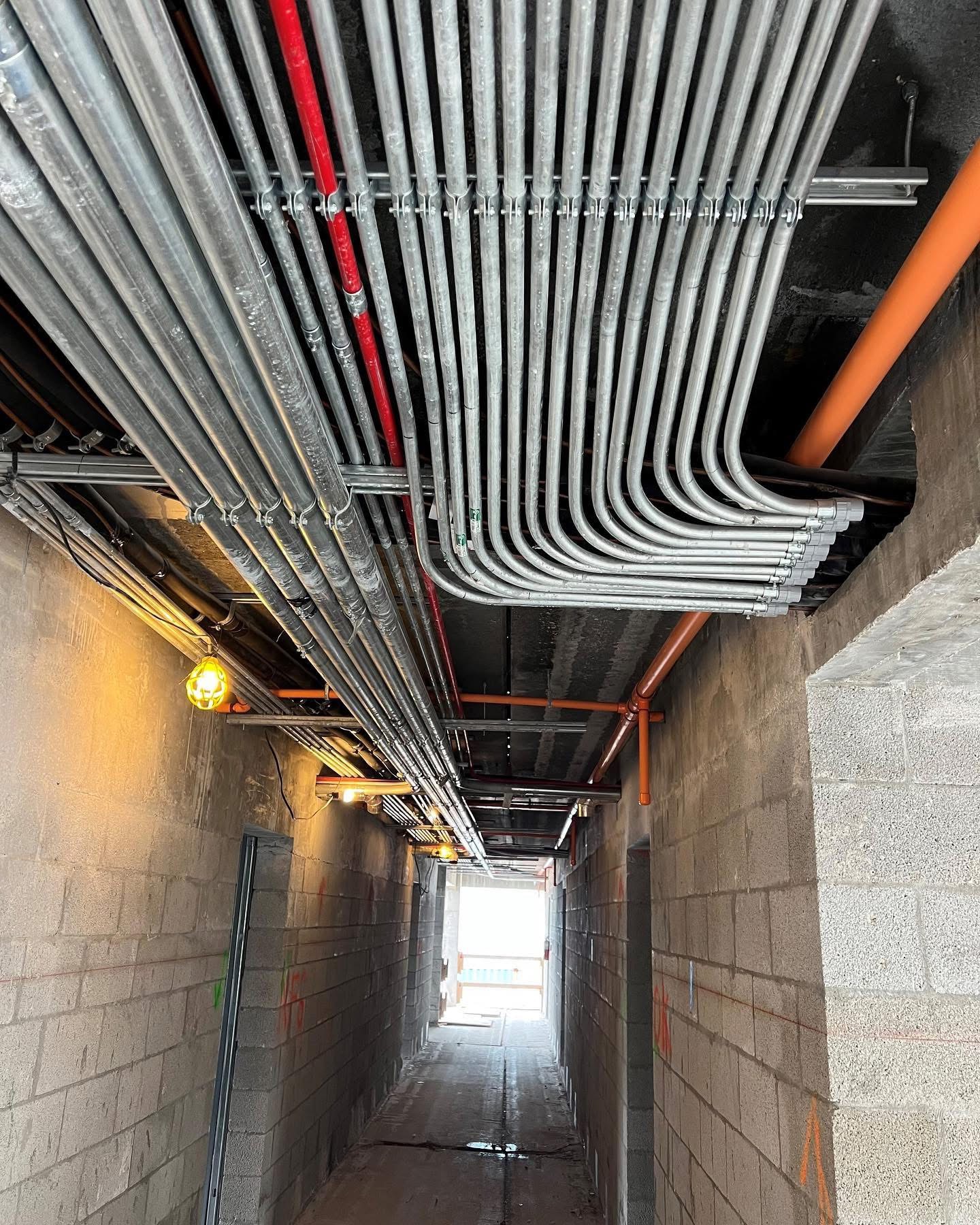 Commercial electrical room featuring rigid steel conduits and three-phase disconnect switches